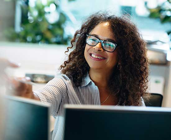 Woman at desk handing something to person.