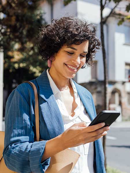 Woman looking at phone outside.