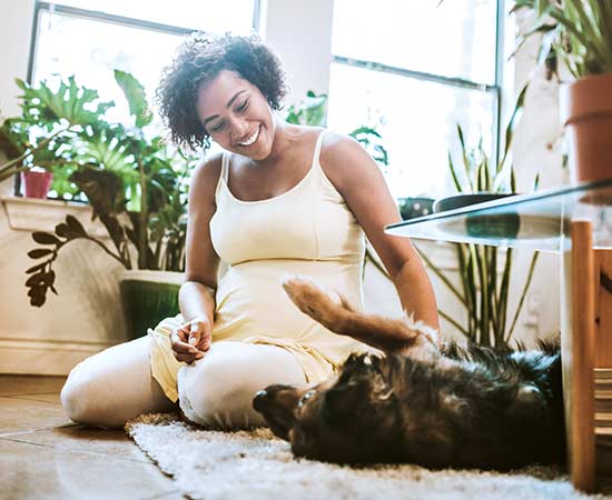Woman sitting on floor with dog in living room.