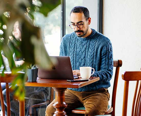 Man using laptop in cafe.